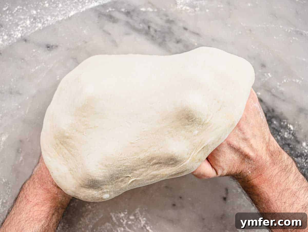 Perfect Ooni Pizza Dough Formula 29 stretching the pizza dough on hand knuckles