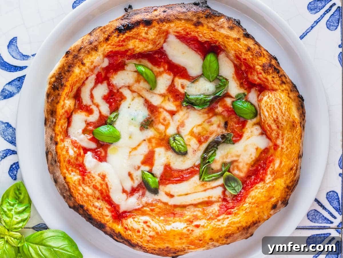 Perfect Ooni Pizza Dough Formula 35 Ooni pizza on a white plate with fresh basil