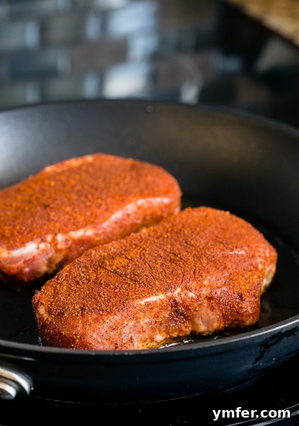 Close-up of golden-brown spiced pork chops with a side of creamy mashed sweet potatoes and fresh charred poblano apple salsa.