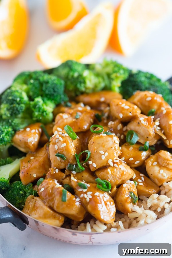 This 20 minute healthier orange chicken is the perfect weeknight dish. Why pay for take out when you can make this quick and easy dish from scratch. Trust me, you'll LOVE this dish it's seriously that EASY! Healthier Orange Chicken served with fresh broccoli and sesame seeds, showcasing a delicious homemade meal.