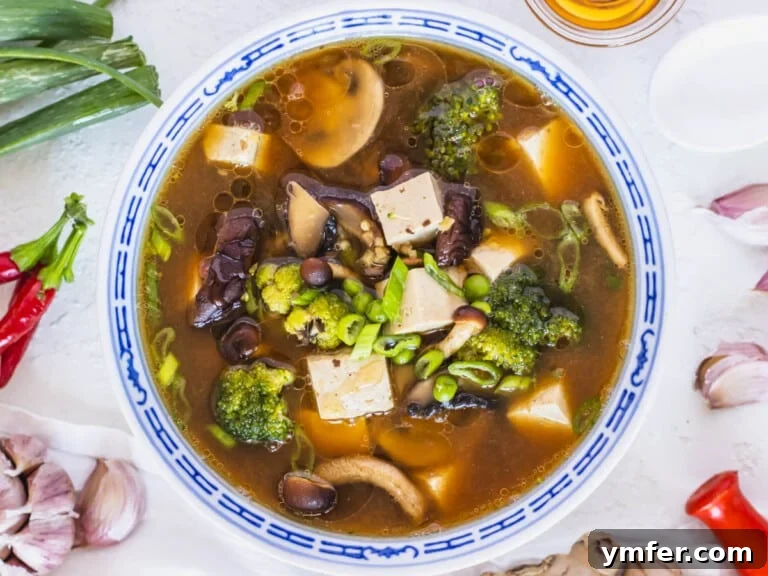 Healthy Asian Kitchen 36 Tofu soup recipe in a blue bowl with garlic on the side