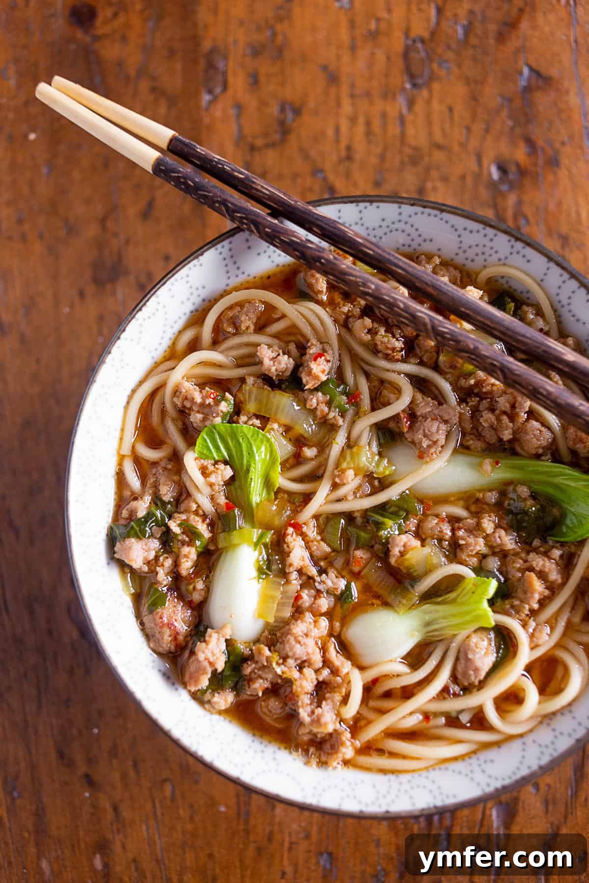 Blazing Pork Noodle Delight 5 A close-up of a Spicy Pork Noodle Bowl in a ceramic bowl, showing the texture of the noodles and greens.
