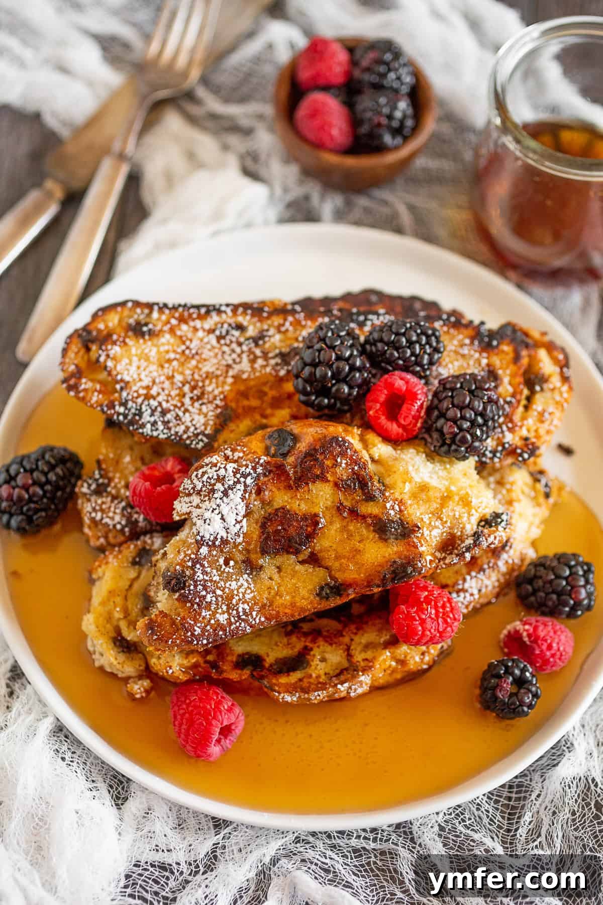 Emerald Isle French Toast 2 Golden Irish Soda Bread French Toast stacked on a plate with fresh berries and powdered sugar.