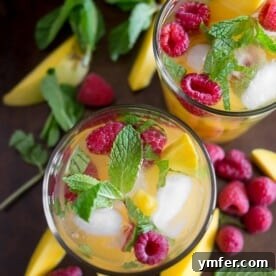 Tropical Raspberry Mango Sangria 3 raspberry mango sangria in a glass with fruit around the glasses on a tray