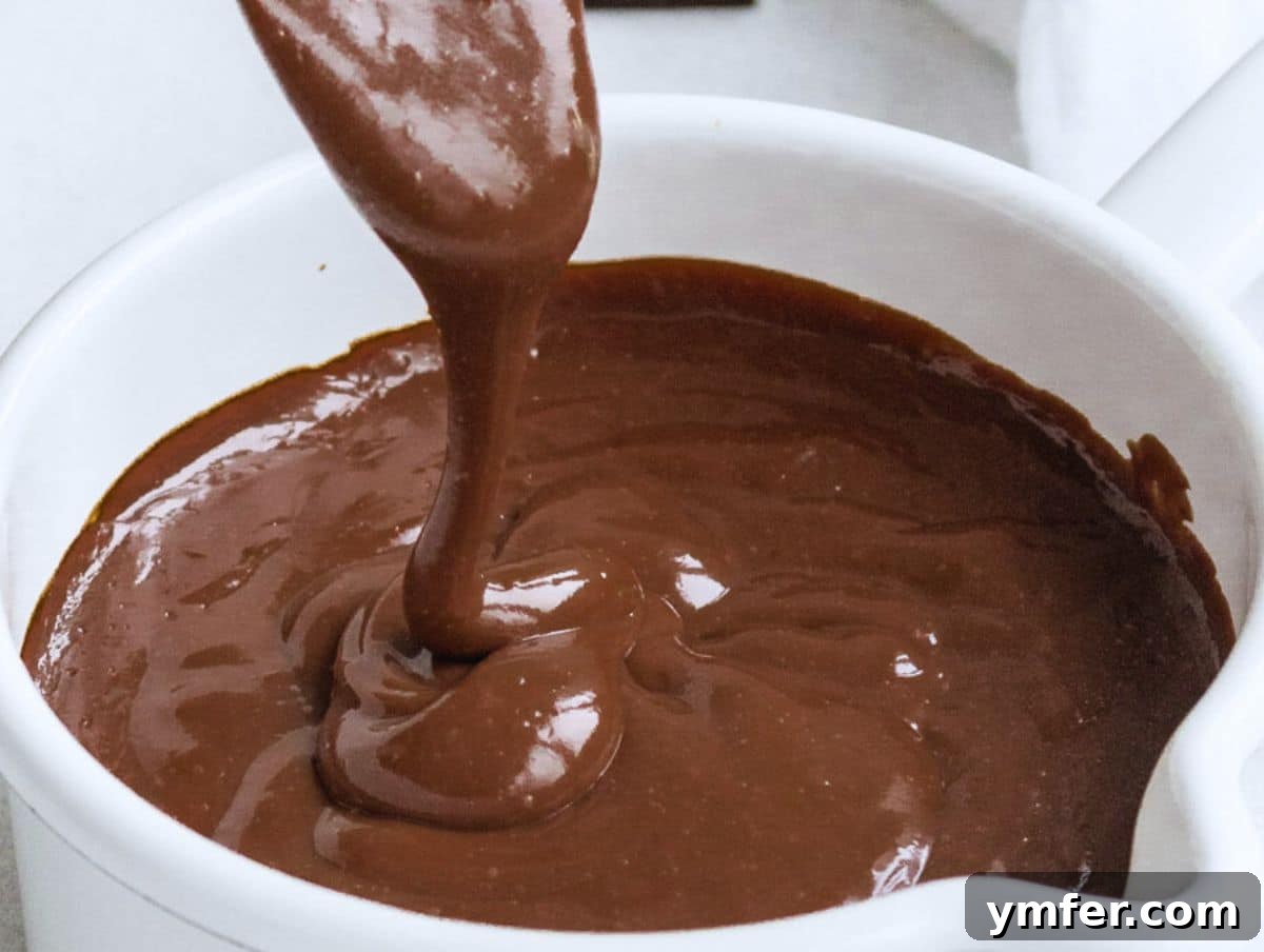 Decadent Chocolate Custard 3 A spoonful of creamy chocolate custard being lifted from a white pot, showcasing its smooth texture.