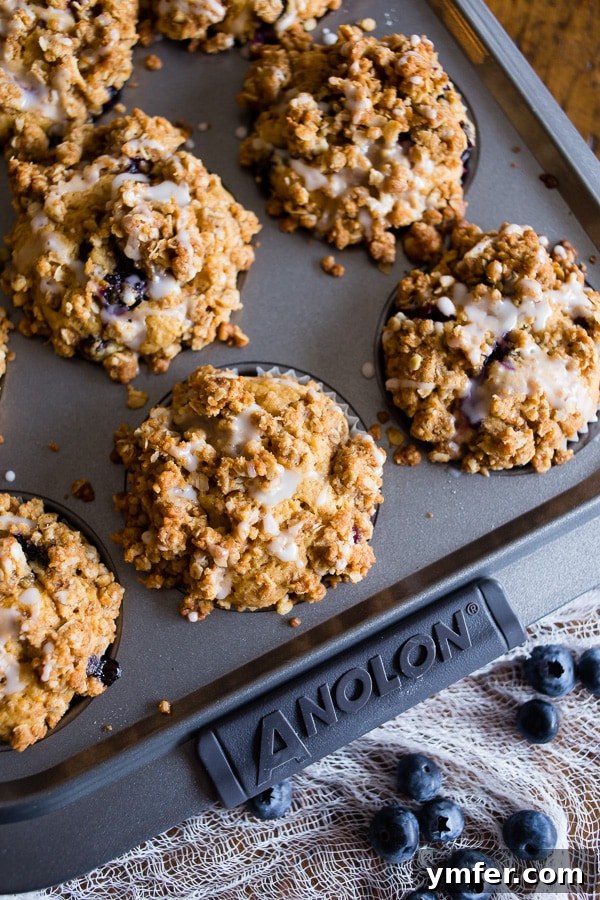 Zesty Lemon Thyme Blueberry Muffins 4 Blueberry Lemon Thyme Muffins baking in a muffin tin, with streusel topping visible.