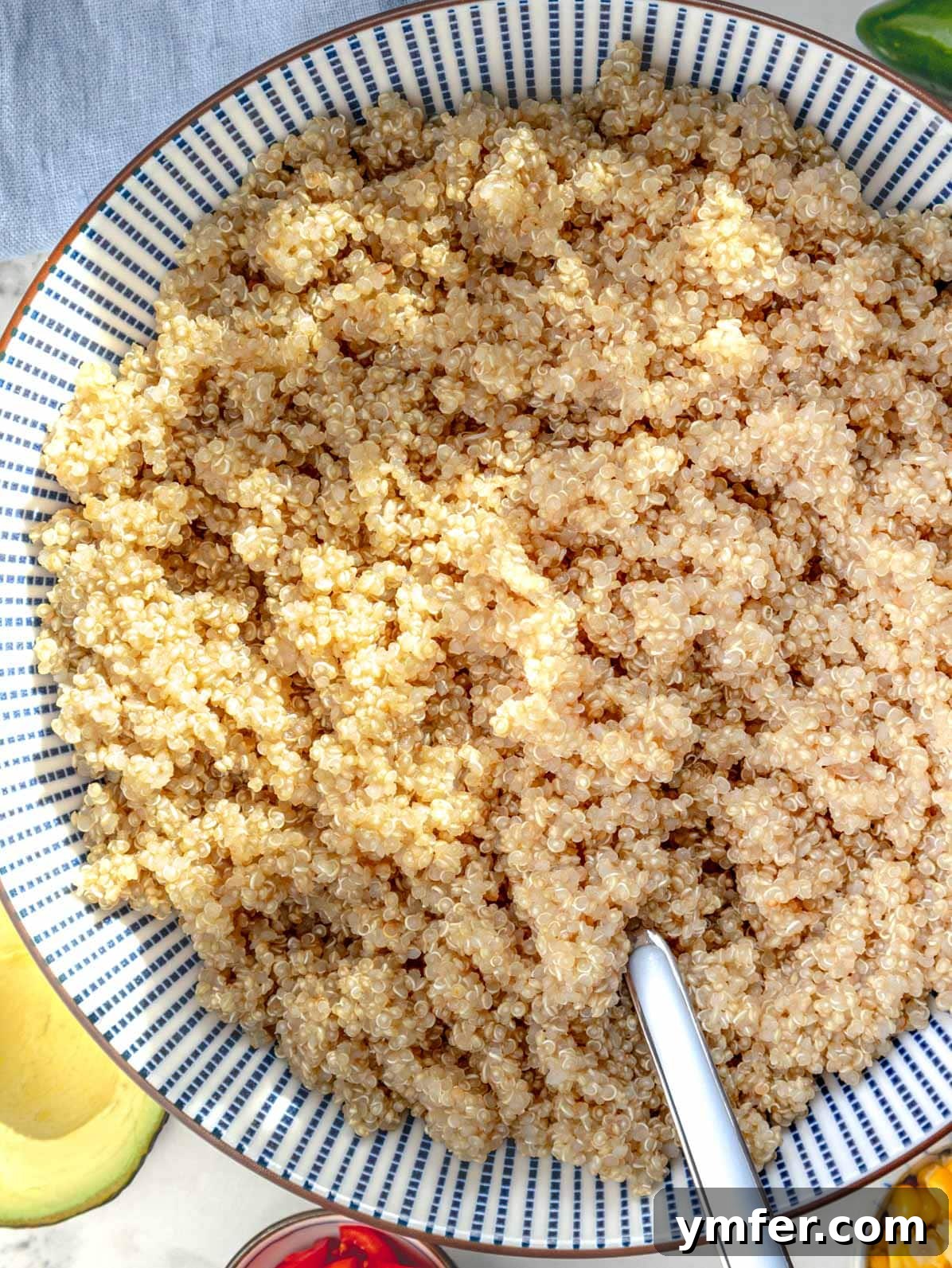 Mastering Perfectly Cooked Quinoa 2 Cooked quinoa in a blue bowl with a fork, ready to be enjoyed as a healthy meal.