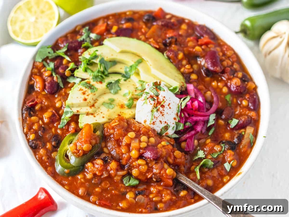 30 Dutch Oven Feasts 7 lentil chili in a white bowl with avocado and pickled red onions