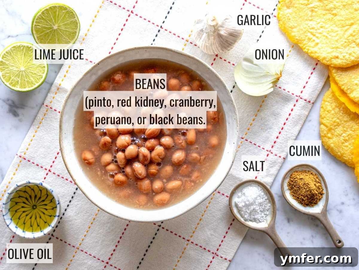 Savory Bean Mash 5 A selection of fresh ingredients including beans, onion, garlic, jalapeño, cumin, lime, and cilantro, laid out for refried beans preparation