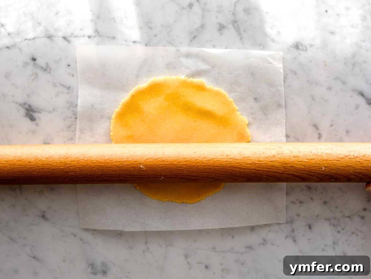 Handcrafted Corn Wraps 8 Detailed image of rolling out a corn tortilla with a rolling pin between two sheets of parchment paper