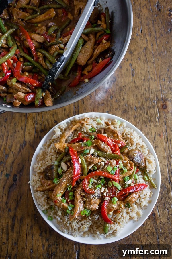 Chili Garlic Pork Wok Toss 5 A completed serving of Spicy Garlic Pork Stir Fry on a plate with rice, garnished with chopped peanuts and green onions.