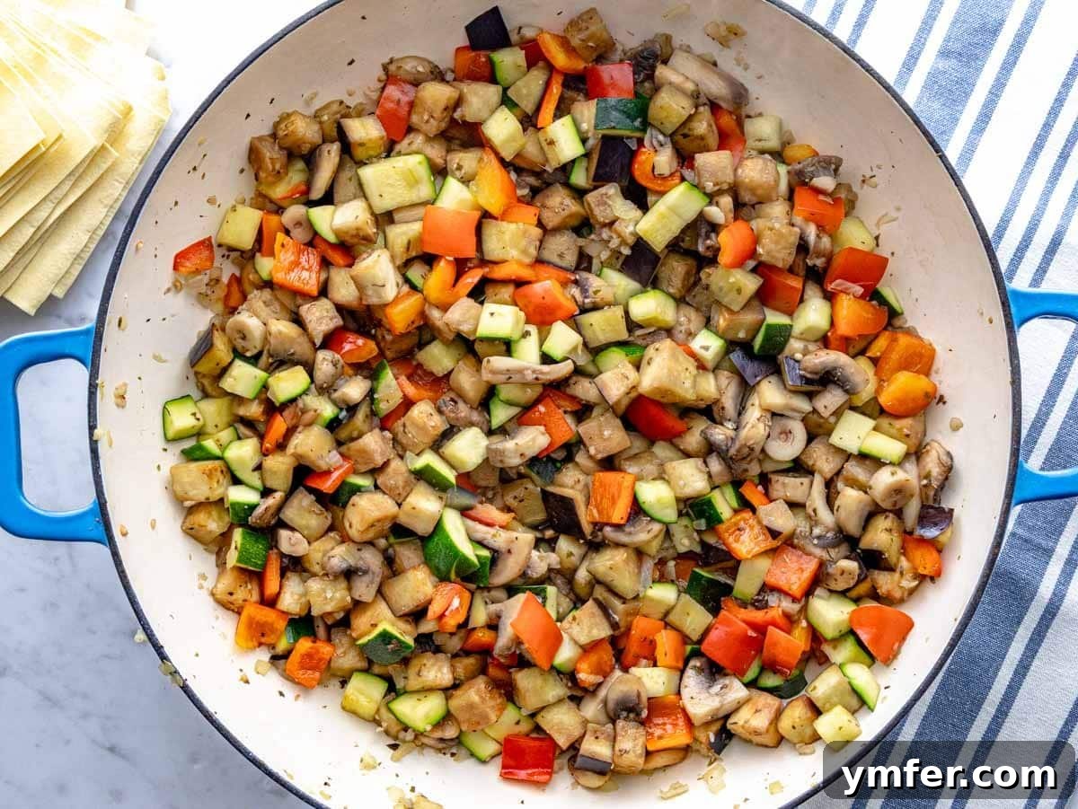 Garden Lasagna 6 Colorful diced vegetables, including eggplant, zucchini, bell pepper, and mushrooms, actively sautéing in a large skillet, releasing their aromas.