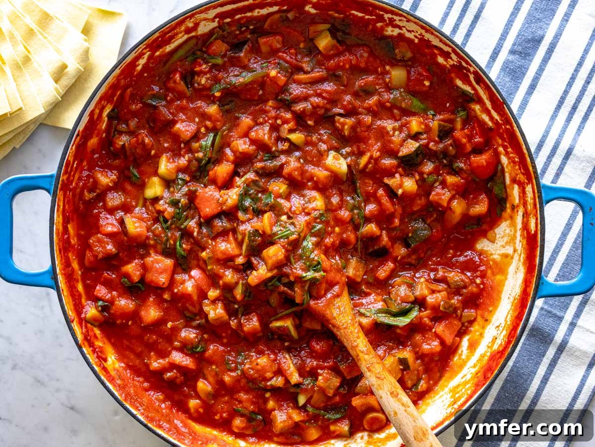 Garden Lasagna 7 A close-up view of the rich tomato sauce with perfectly cooked vegetables and fresh basil leaves simmering in a skillet.
