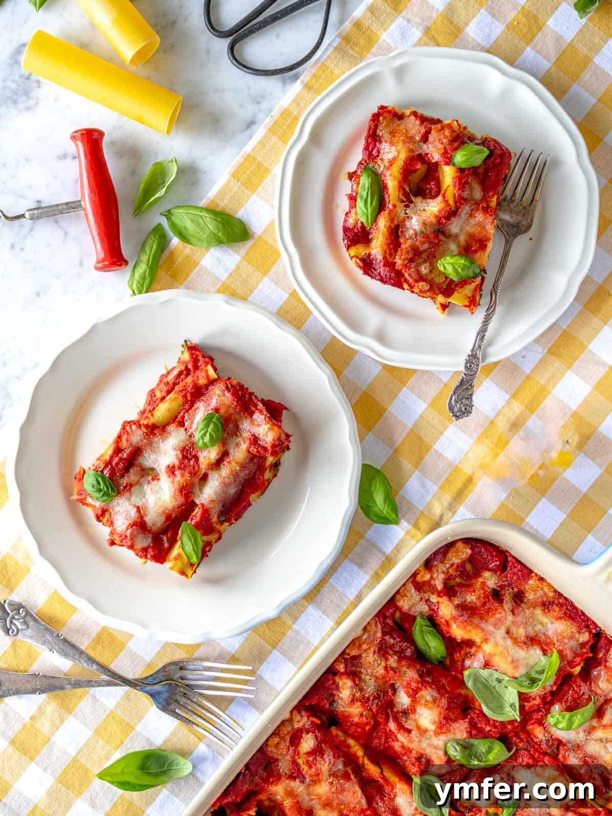 Hearty Stuffed Pasta Bake 2 Baked cannelloni (or manicotti) in a casserole dish, with two servings plated alongside, garnished with fresh basil.