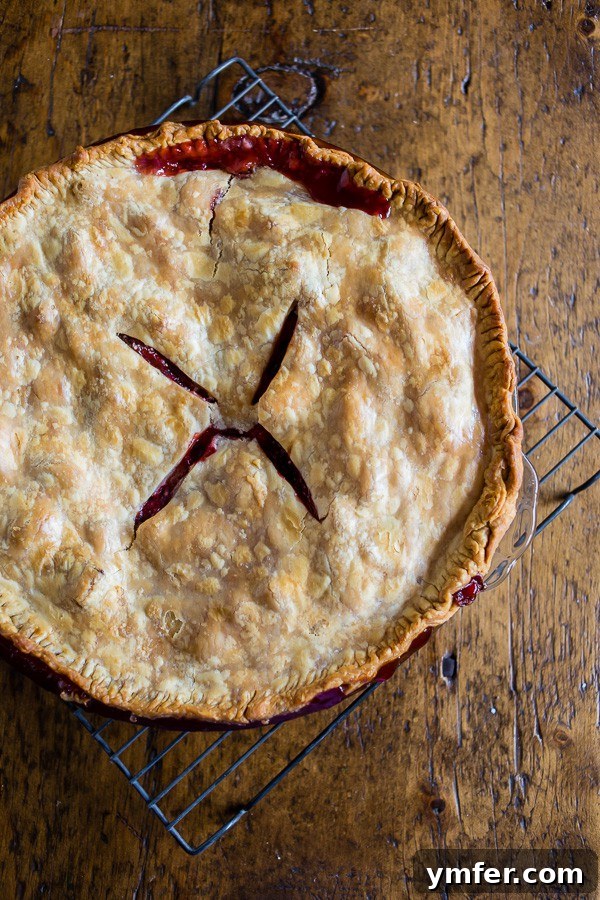 A freshly baked strawberry rhubarb pie cooling on a wire rack, its steam gently rising, hinting at the warm goodness within.