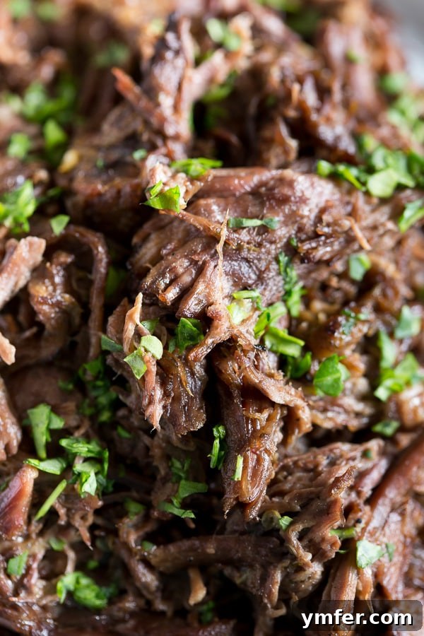 The Ultimate Homemade Mississippi Pot Roast 4 Shredded Homemade Mississippi Pot Roast in a close-up shot, showcasing its tender texture.