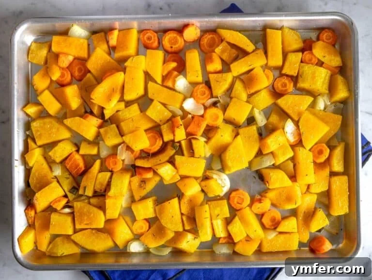 Roasted butternut squash and carrots on a baking tray, golden brown and tender.