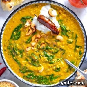 Dal in a blue bowl with a silver spoon, ready to be eaten.