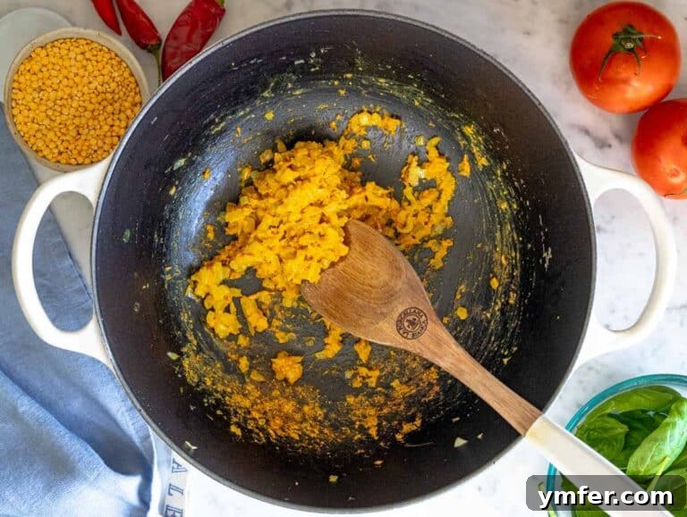 The initial flavor base for dal, showing sautéed onions, ginger, garlic, and spices in a pot.