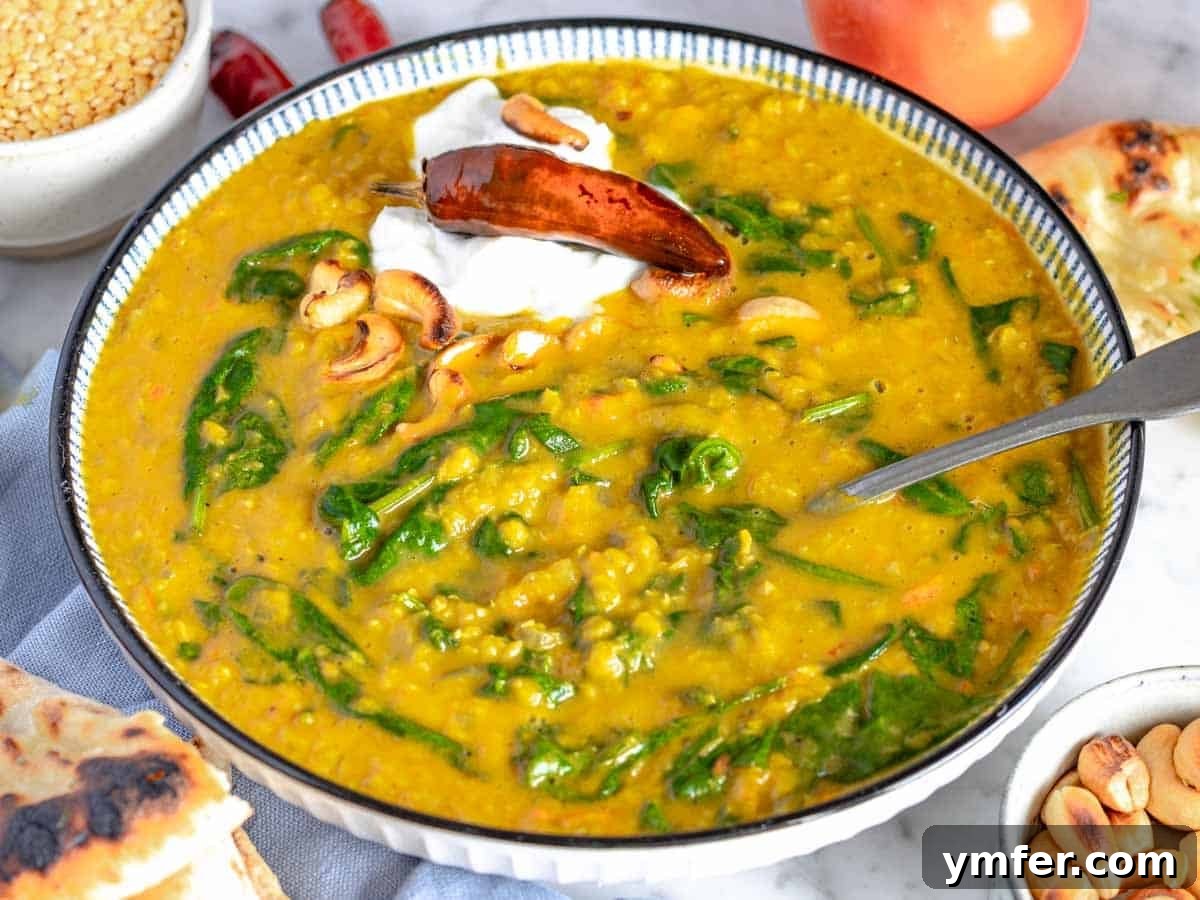 A bowl of creamy yellow dal, richly garnished with fresh cilantro, a dollop of yogurt, and crunchy toasted cashews, ready to be enjoyed.