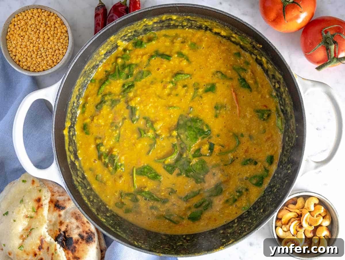 A large pot filled with creamy split lentil dal, infused with spinach and aromatic spices, ready to be portioned and served.