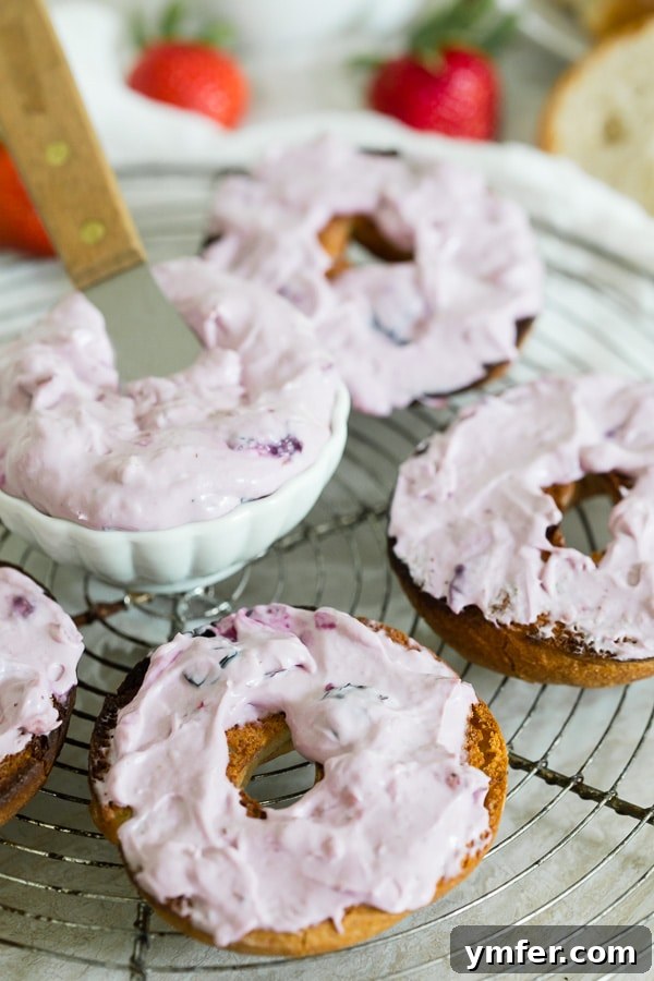 Creamy Berry Indulgence 2 Vibrant Roasted Berry Cream Cheese spread generously on toasted bagels, garnished with fresh berries.