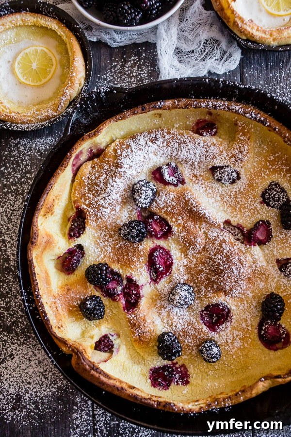 Blackberry Lemon Dutch Baby in a skillet, showcasing its puffed edges.