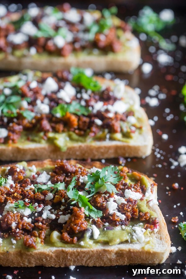 Gourmet Chorizo Cotija Guacamole Toast 4 Three slices of Chorizo Cotija Guacamole Toast on a wooden board