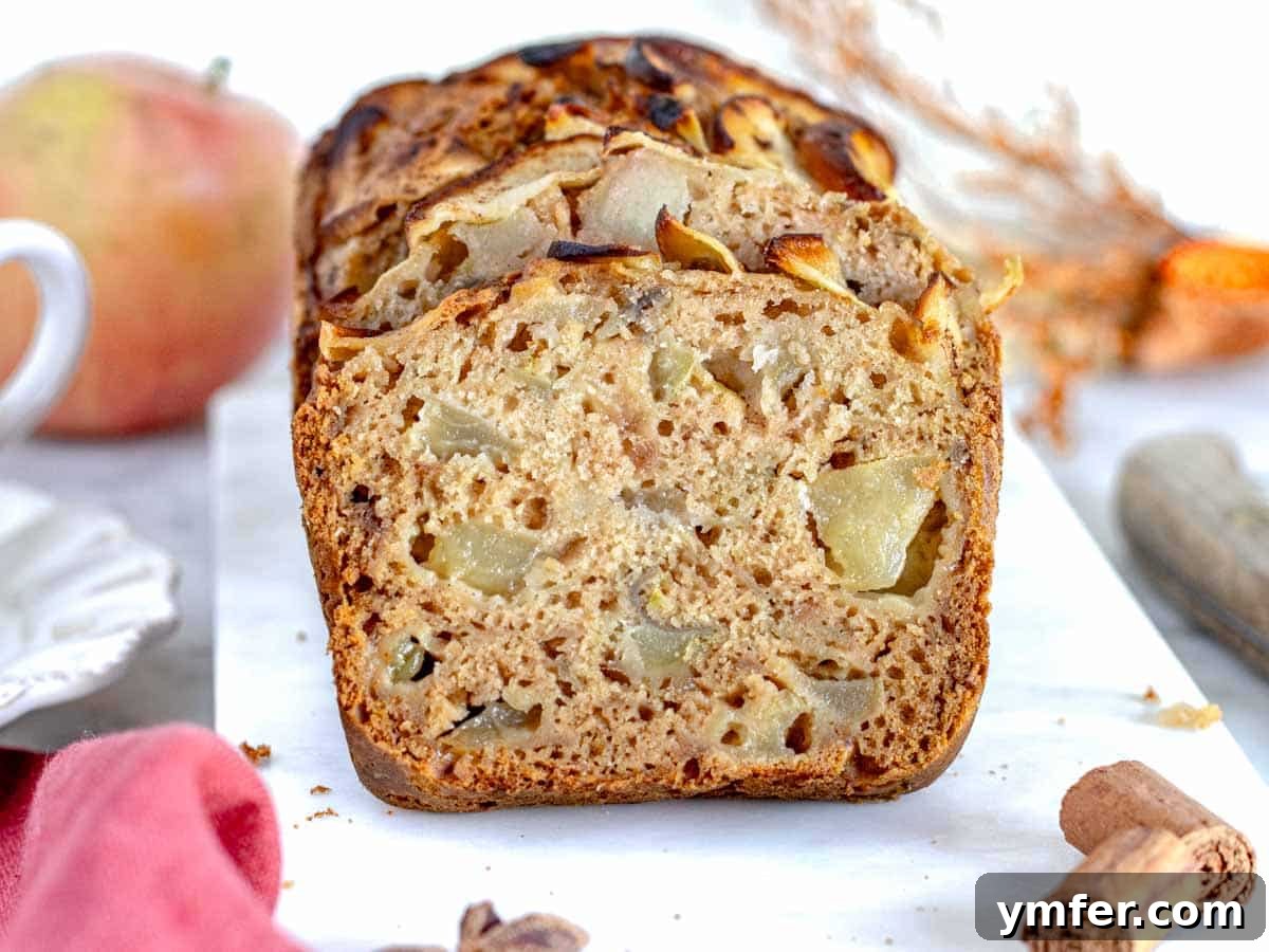 A moist slice of apple bread, revealing visible apple pieces and a tender crumb.