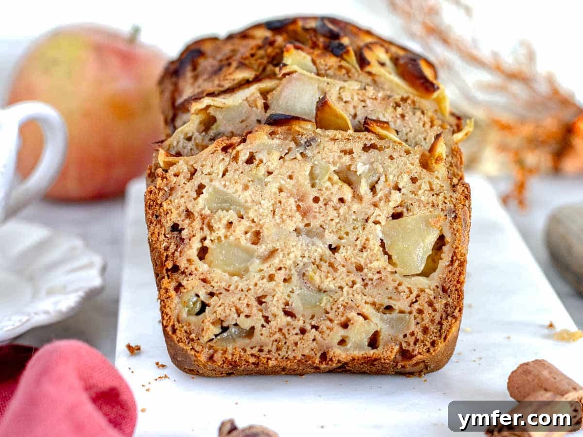 A freshly baked apple bread on a marble cutting board, ready to be sliced.