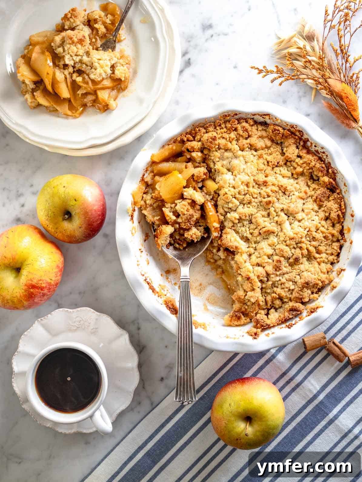 Golden Apple Crumble Perfection 2 Apple crumble with a silver spoon and a cup of coffee