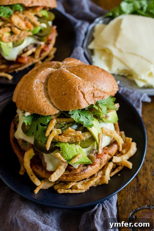 A vibrant Baja burger on a plate, generously topped with fresh cilantro, golden crispy onions, and creamy avocado slices, inviting a first delicious bite.