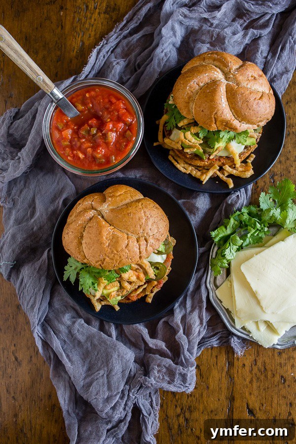 A beautifully composed Baja burger resting on a plate with a grey napkin, highlighting its fresh, colorful toppings.