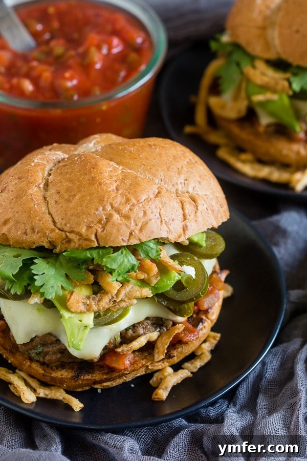 A close-up shot of a Baja burger, beautifully topped with melted cheese and fresh cilantro, ready to be enjoyed.
