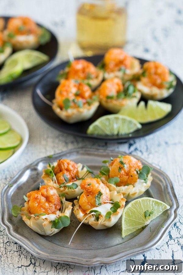 Crispy Tequila Lime Shrimp Phyllo Cups 2 Tequila Lime Shrimp Phyllo Cups arranged artfully on a white plate with fresh lime slices and sprigs of cilantro, showcasing a perfectly golden phyllo cup filled with shrimp and sauce.