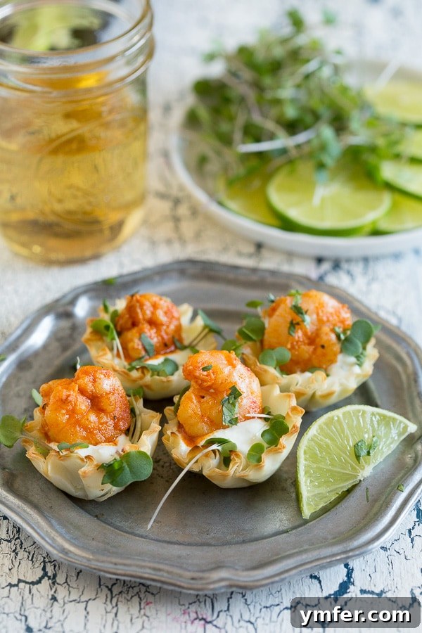Crispy Tequila Lime Shrimp Phyllo Cups 3 A close-up shot of Tequila Lime Shrimp Phyllo Cups on a plate, with a blurred background showing a cold beverage, suggesting a relaxed party atmosphere.