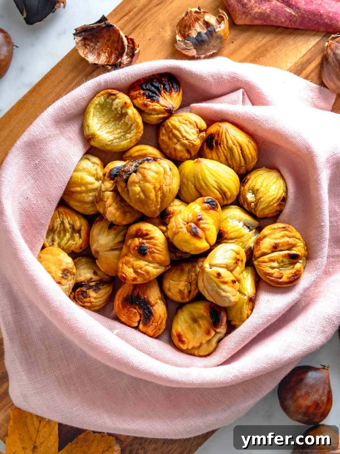 Fireside Roasted Chestnuts 2 Roasted chestnuts wrapped in a kitchen cloth, emitting steam.