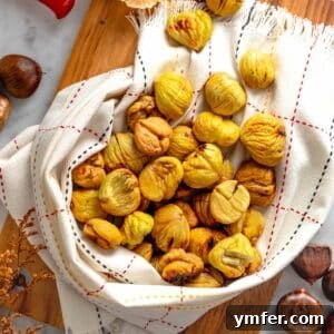Roasted chestnuts wrapped in a kitchen cloth on a cutting board.