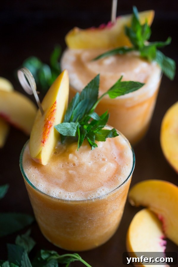 Sweet Peach Tea Bourbon Freeze 4 Two glasses of Peach Tea Bourbon Slushies with fresh peach slices and mint garnish