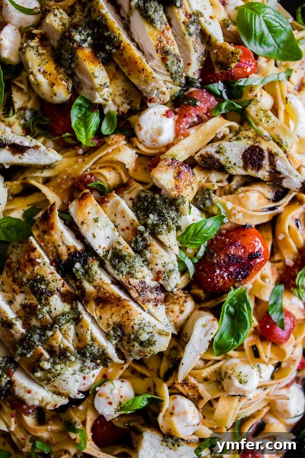 Fresh Caprese Pesto Chicken Pasta 5 Pesto Chicken Caprese Pasta topped with grilled chicken. A close-up shot showing the textures and layers of the dish.