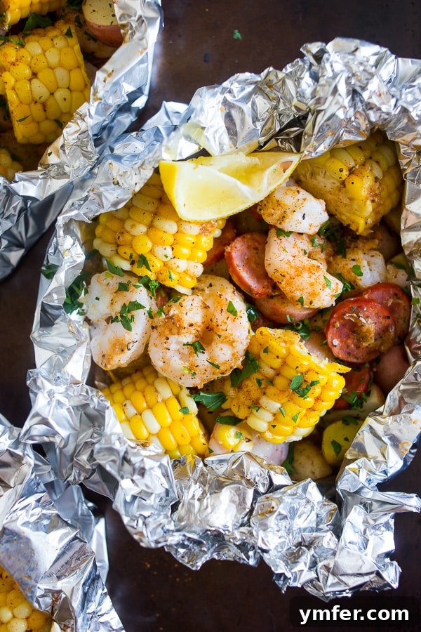Low country boil foil packets ready for cooking on a sheet pan, tightly wrapped.