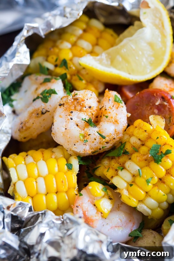 Close up view of cooked shrimp and corn inside an opened low country boil foil packet, garnished with fresh parsley.