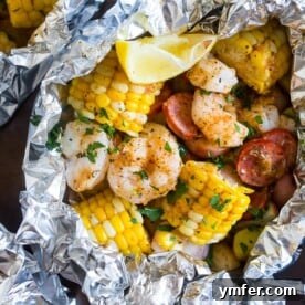 Low country boil foil packets on a sheet pan wrapped in foil, ready to cook.