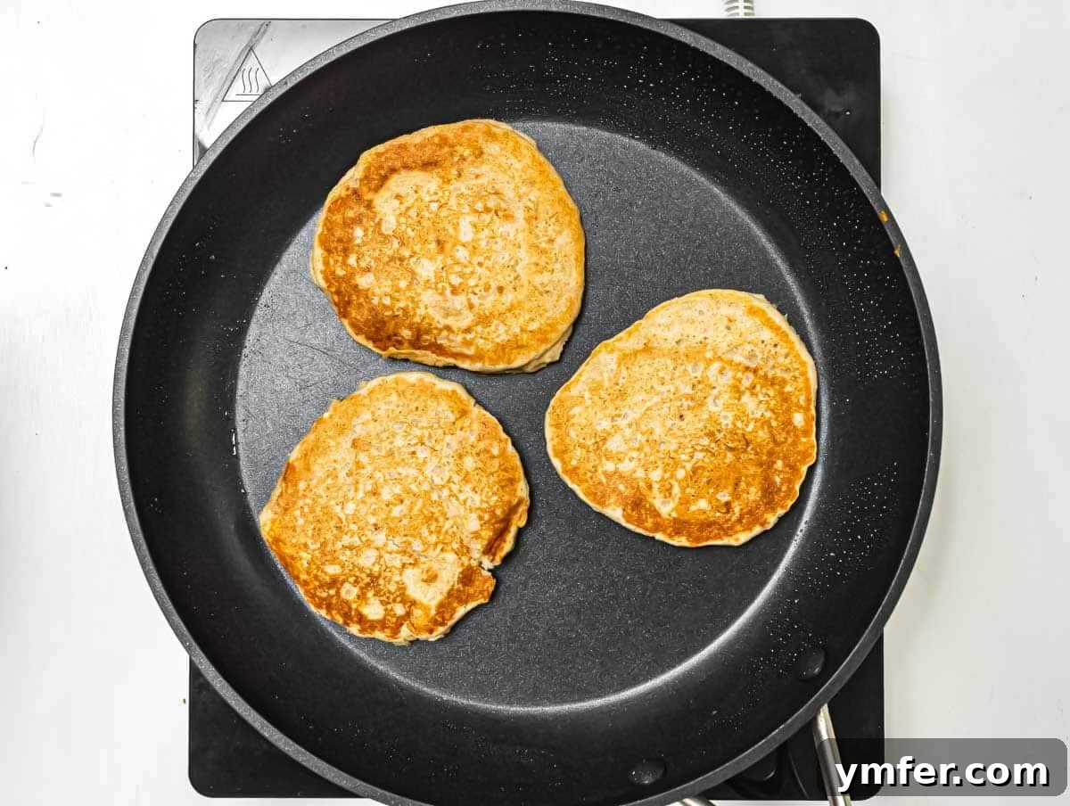 Hearty Oat Flapjacks 5 Oatmeal pancakes cooking on a non-stick pan.