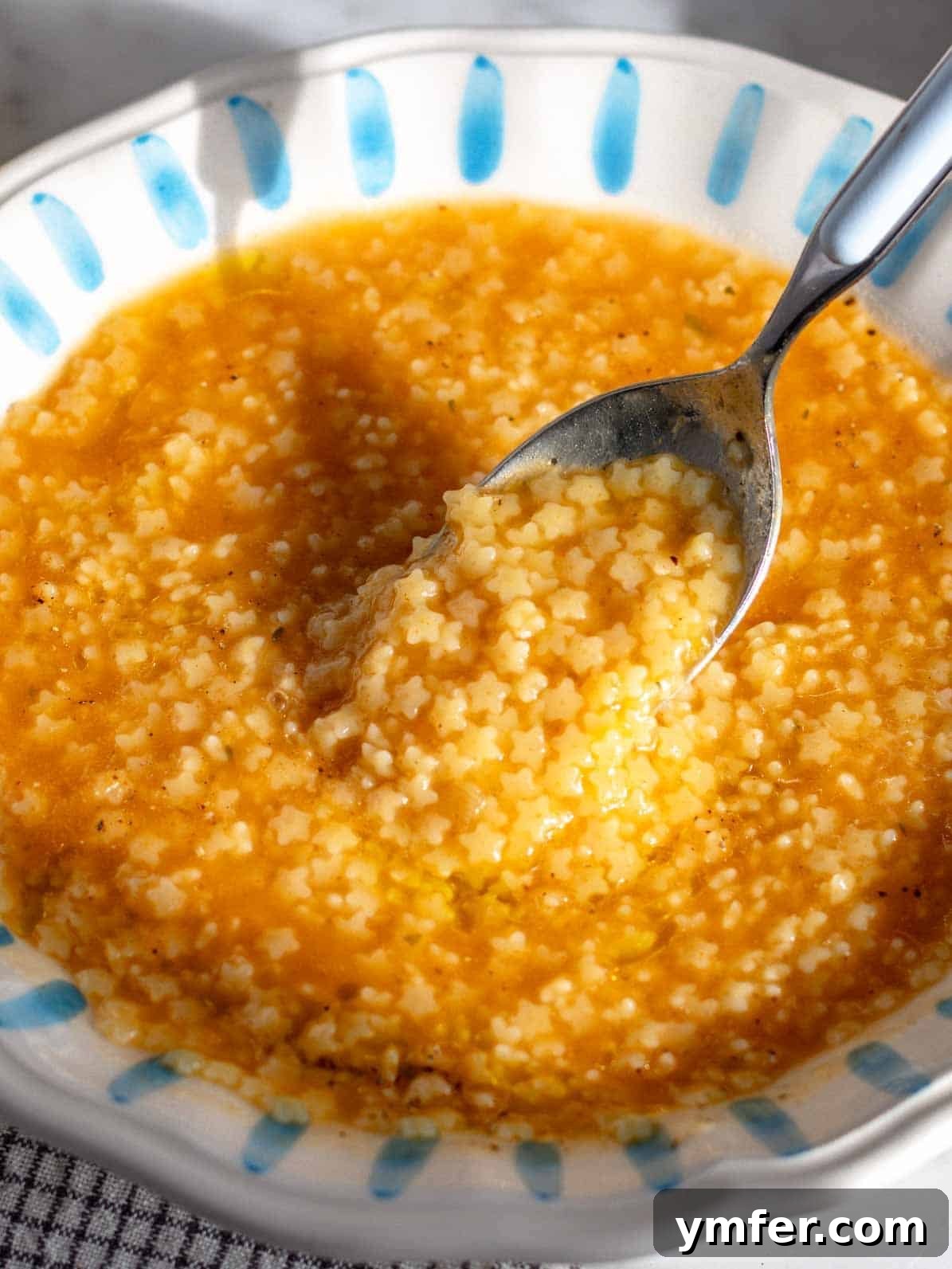 Soothing Small Pasta 2 A bowl of creamy Italian pastina soup with a spoon, ready to be enjoyed.