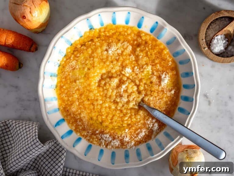 Pastina served in a bowl with grated parmesan cheese and olive oil.