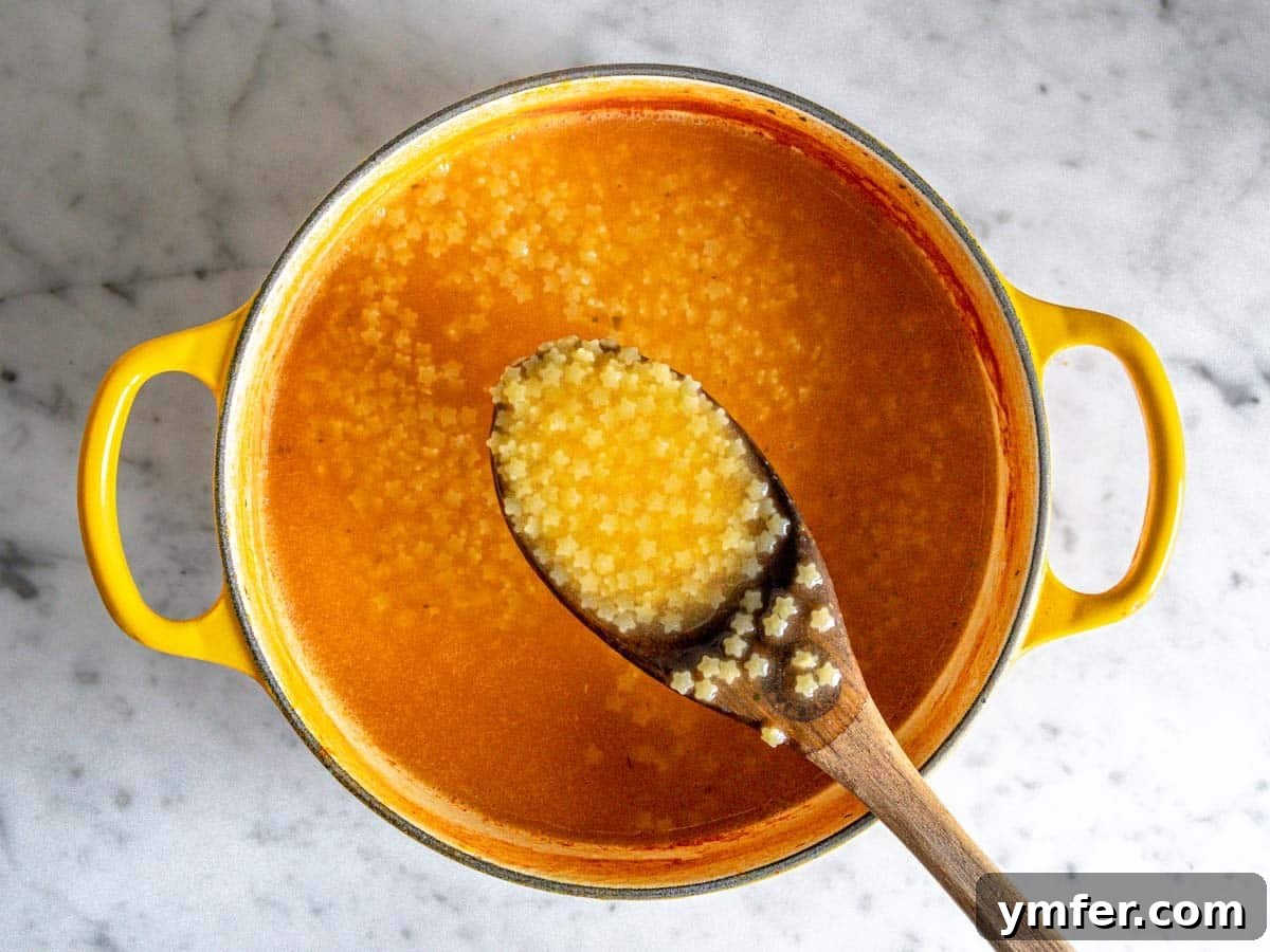 Soothing Small Pasta 10 Creamy Pastina soup simmering in a yellow cast iron pot, showcasing its rich texture.