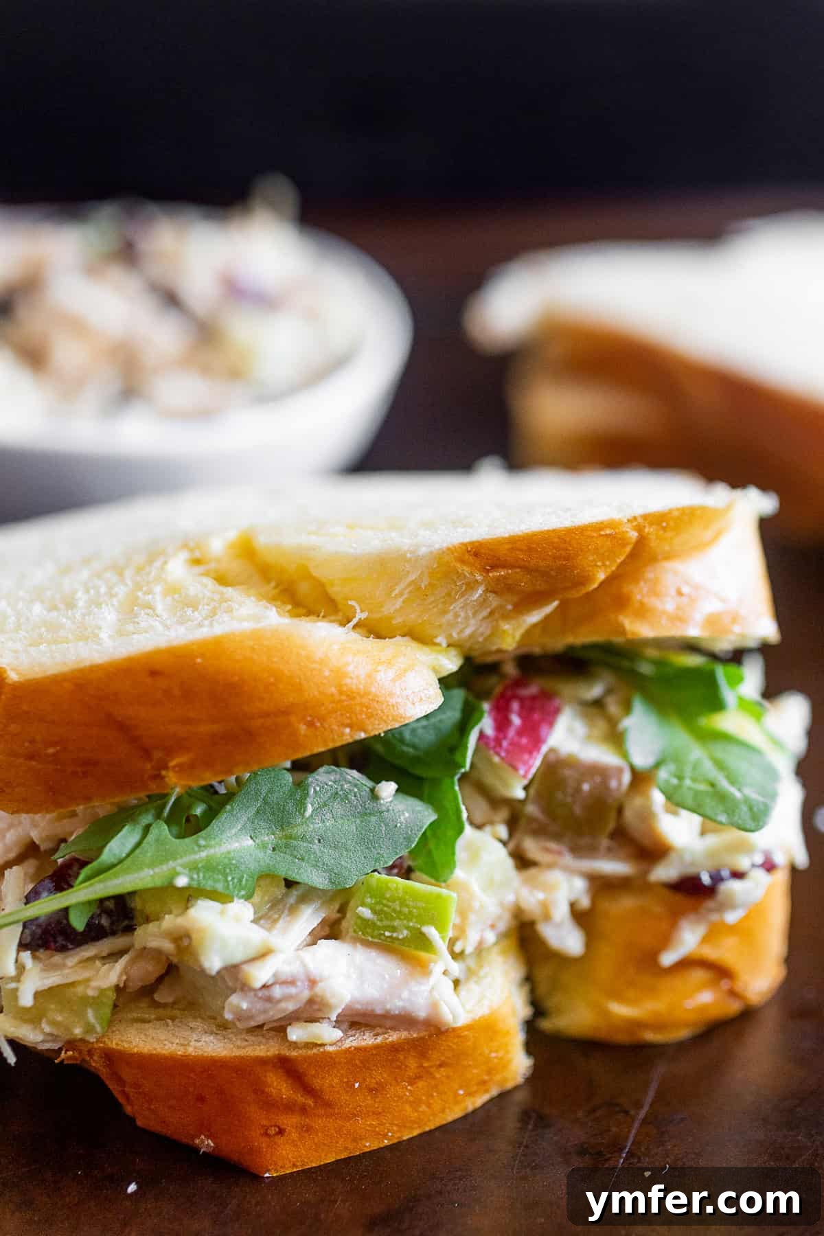 Mediterranean Hummus Chicken Salad 2 Hummus Chicken Salad served generously on a slice of soft white bread, garnished with fresh greens.