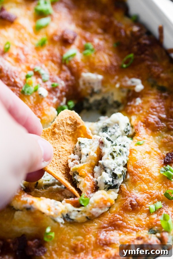 Hot and Bubbly Bacon Spinach Dip 5 A close-up of a serving of the Baked Spinach Bacon Dip on a platter, garnished with fresh green onions and bacon bits, inviting guests to enjoy.