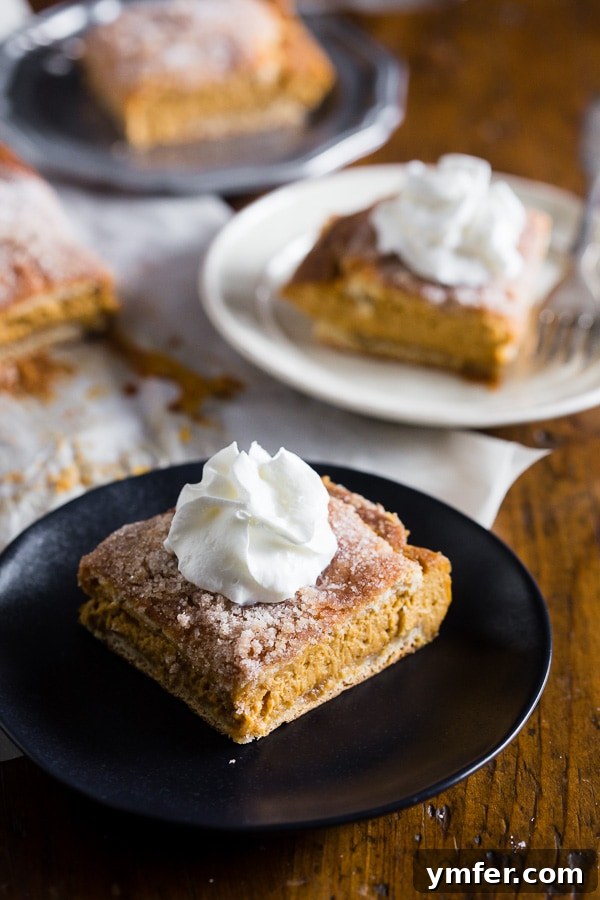 Autumn Churro Pumpkin Cheesecake Dream Bars 4 A single pumpkin churro cheesecake bar served on a plate, generously topped with fluffy whipped cream.